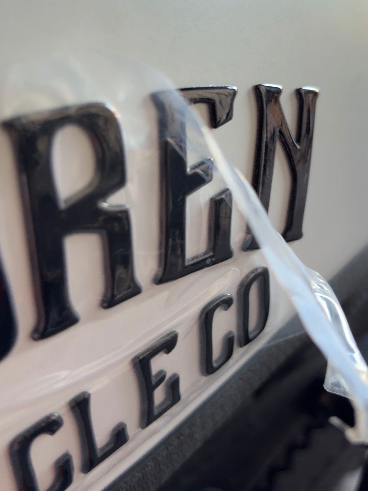 Close-up of a car badge with 'Renault' text on a white background
